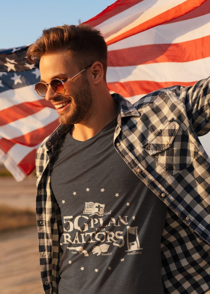 Man holding the American flag and wearing The 5G Plan for Traitors shirt